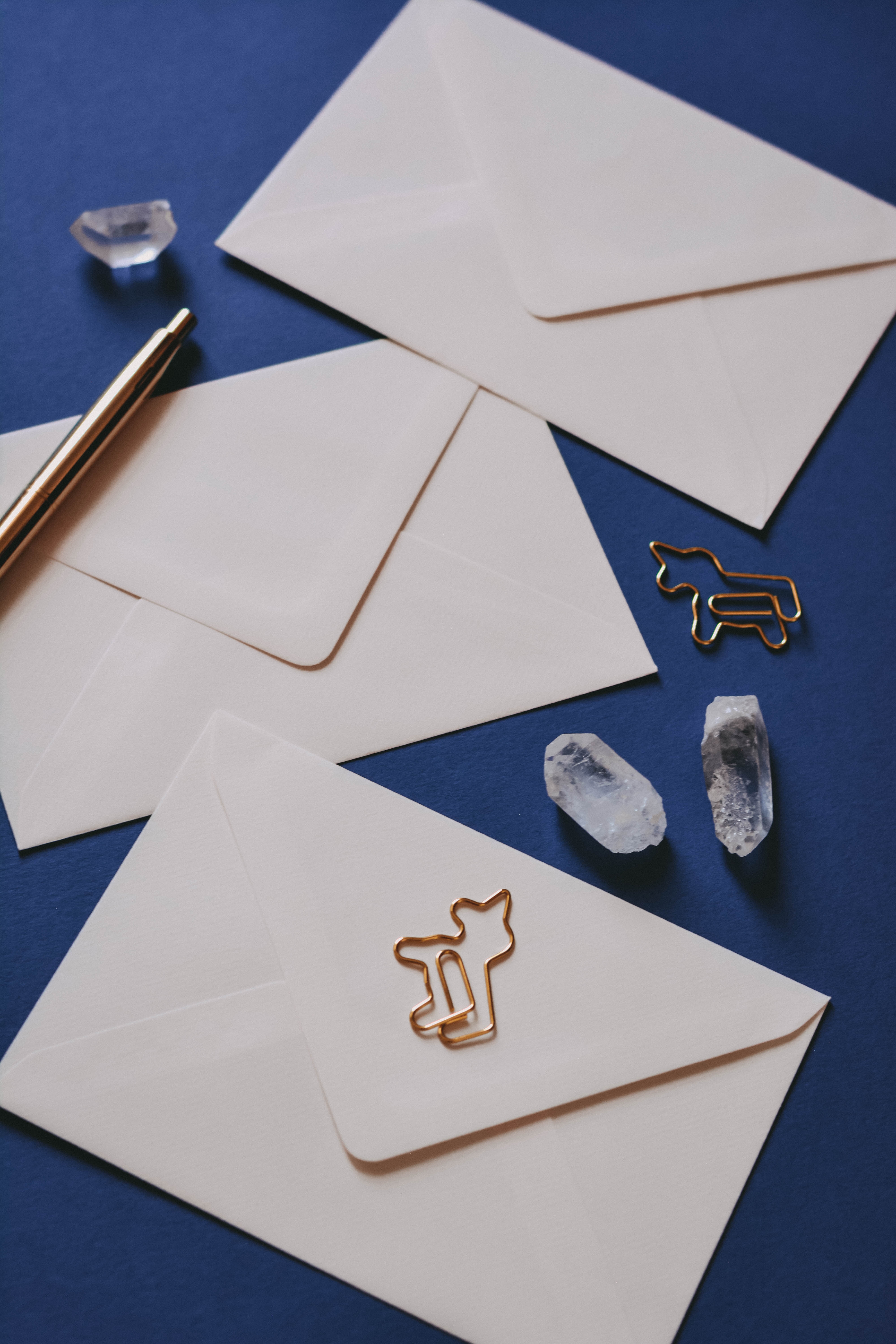 A gold pen, envelope, and crystals arranged on a surface.